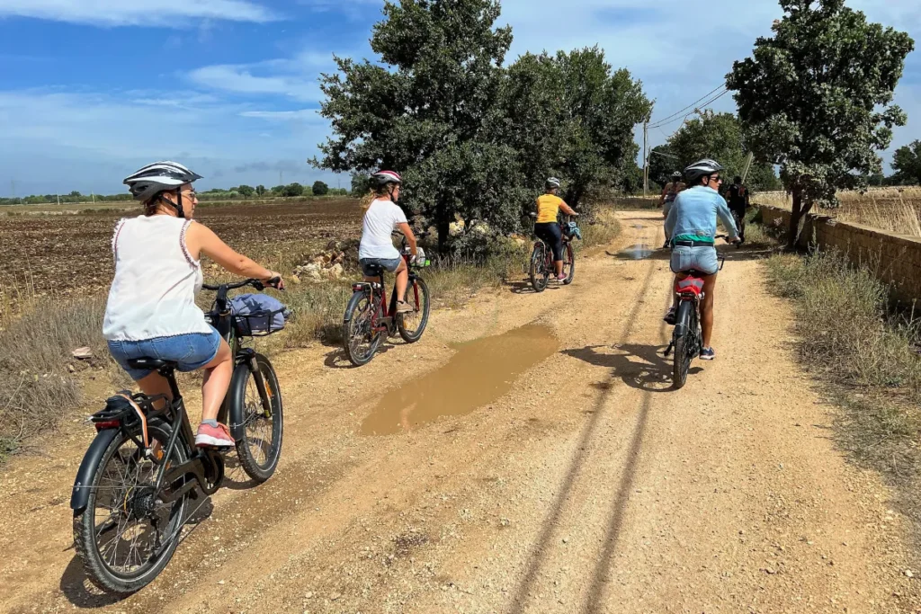 Group pedaling on a dirt trail across the hilly countryside outside Matera