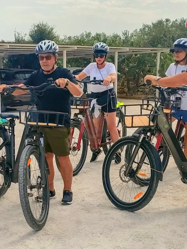 Cyclists pedaling past rows of grapevines under the Puglian sun