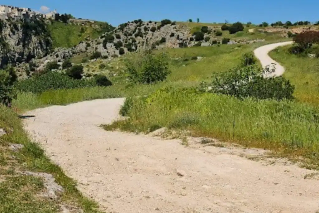 Ebike su sentiero naturale in Puglia, paesaggio collinare e strada sterrata.