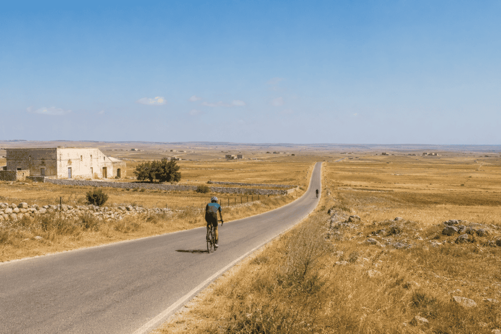 Cyclists on an exposed rural road across the Alta Murgia plateau